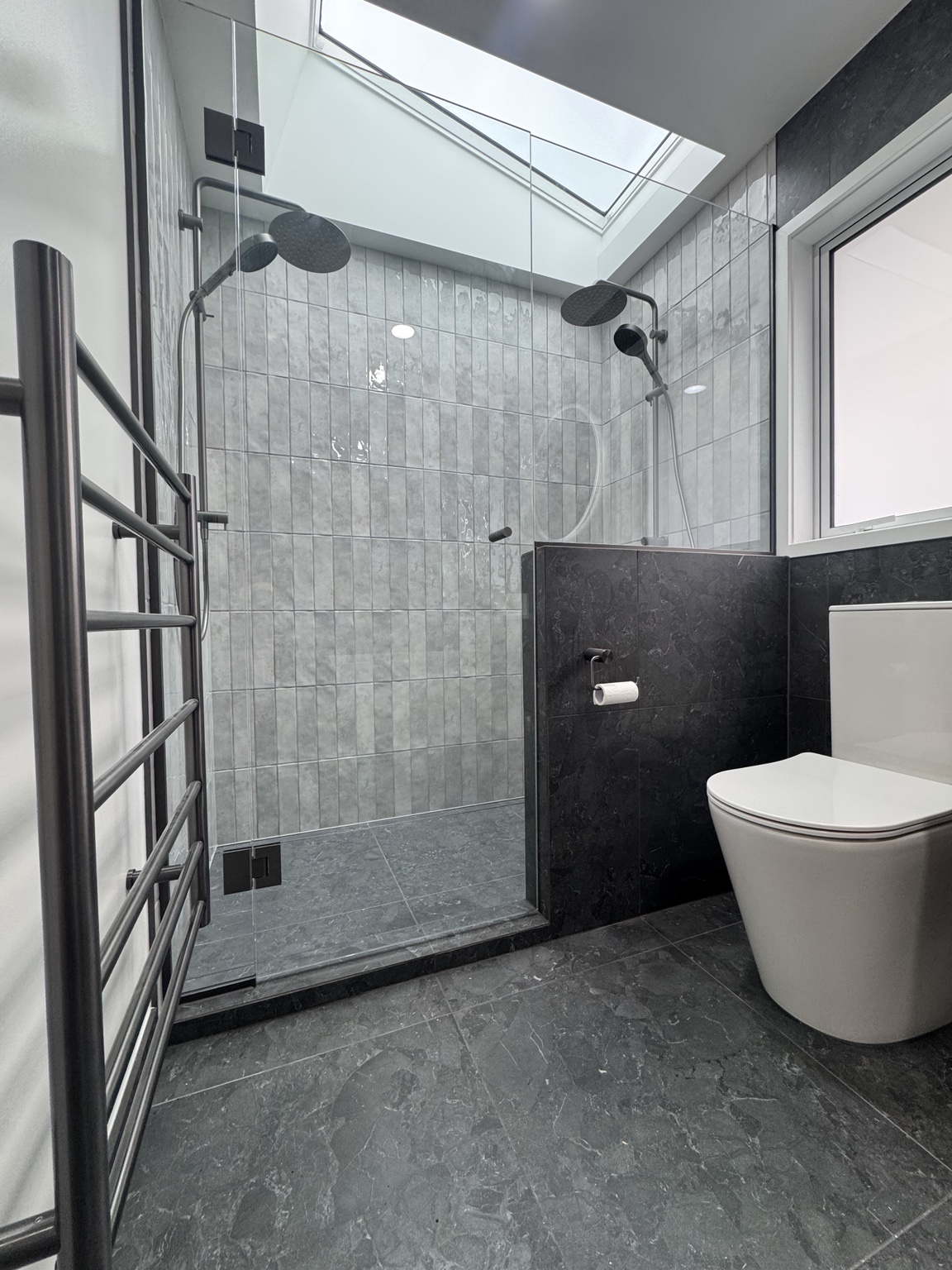 Bathroom Co. project featuring a tiled shower beneath a skylight with considered dark and light finishes